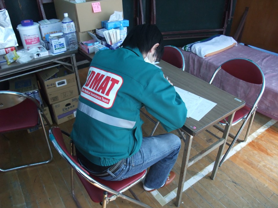 東日本大震災の避難所の救護所で診療録を書く東京DMATの医師 (2011年)